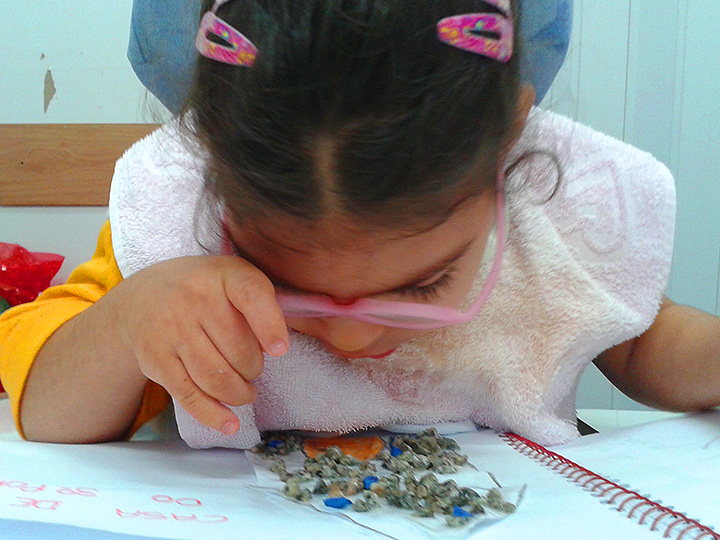 Uma criança com surdocegueira olha em direção a um caderno