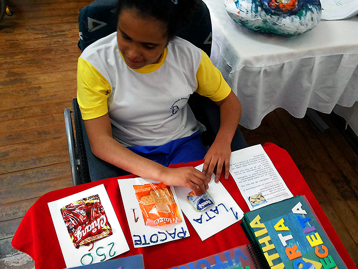 Foto do Ahimsa - Uma garota olha para atividades em papel sobre uma mesa