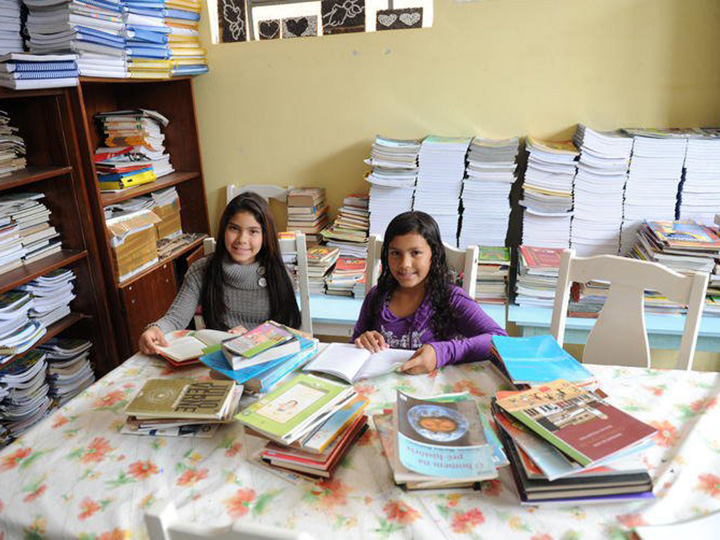 Photo from Projeto Resgate - Two girls smile while exploring books at a library.