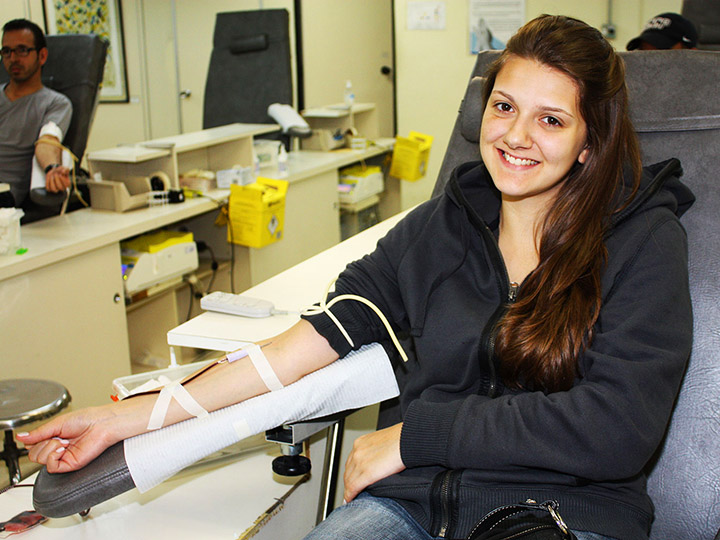 Uma mulher jovam sorri enquanto faz uma doação de sangue