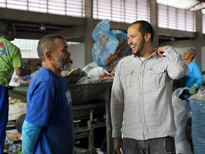 Two men talk in a recycling center background